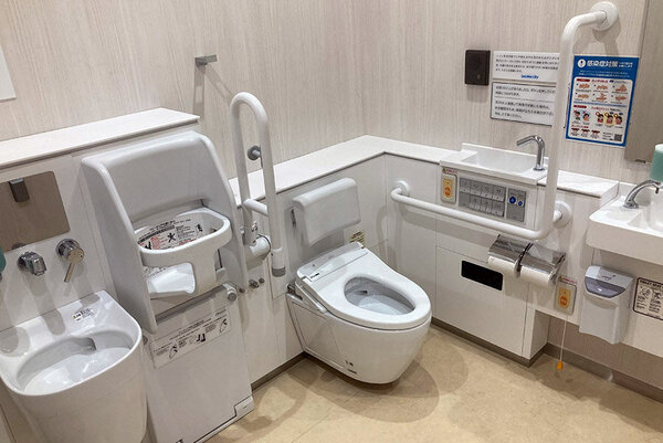 アルパ3F南通り沿い優先トイレの写真、跳ね上げ式手すりや、チャイルドシート、オストメイト対応トイレの設備がある