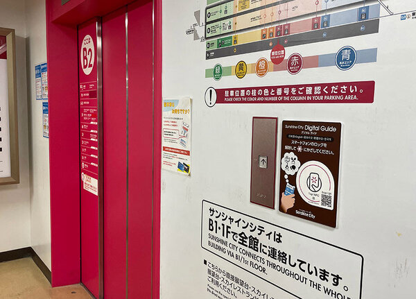 サンシャインシティ駐車場の地下2階のエレベーター前の写真、エレベーターボタンの右横に、デジタルガイドに遷移できるNFCタグが設置されている