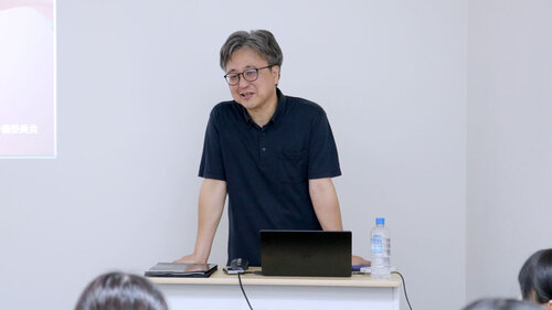 教壇に立ち、受講者に向けて話している尾野