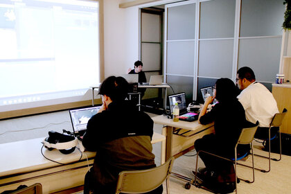 大きなモニターを見ながら講師の話を聞いている三人の受講者の様子