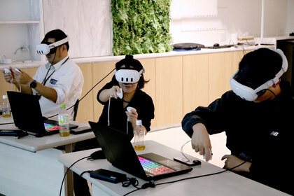 頭にヘッドマウントディスプレイを装着し、手にコントローラーを持って仮想空間上のコンテンツを操作している受講者の様子