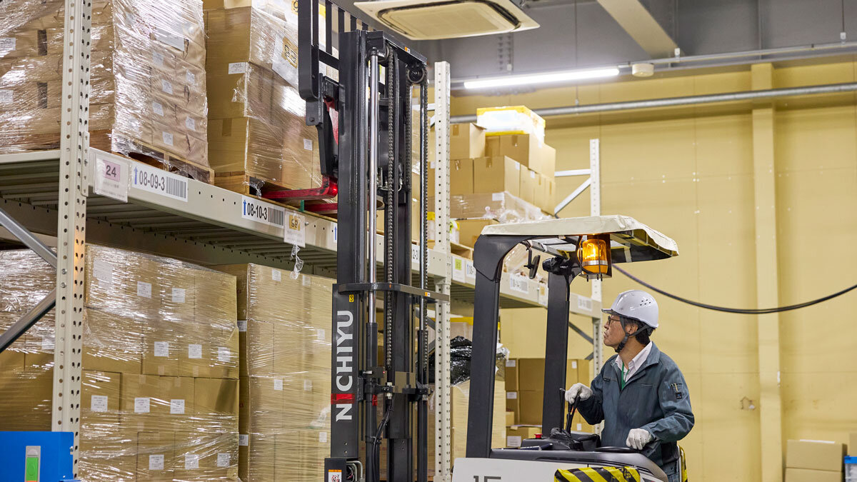 棚の上段の在庫をリフトで持ち上げる従業員の様子