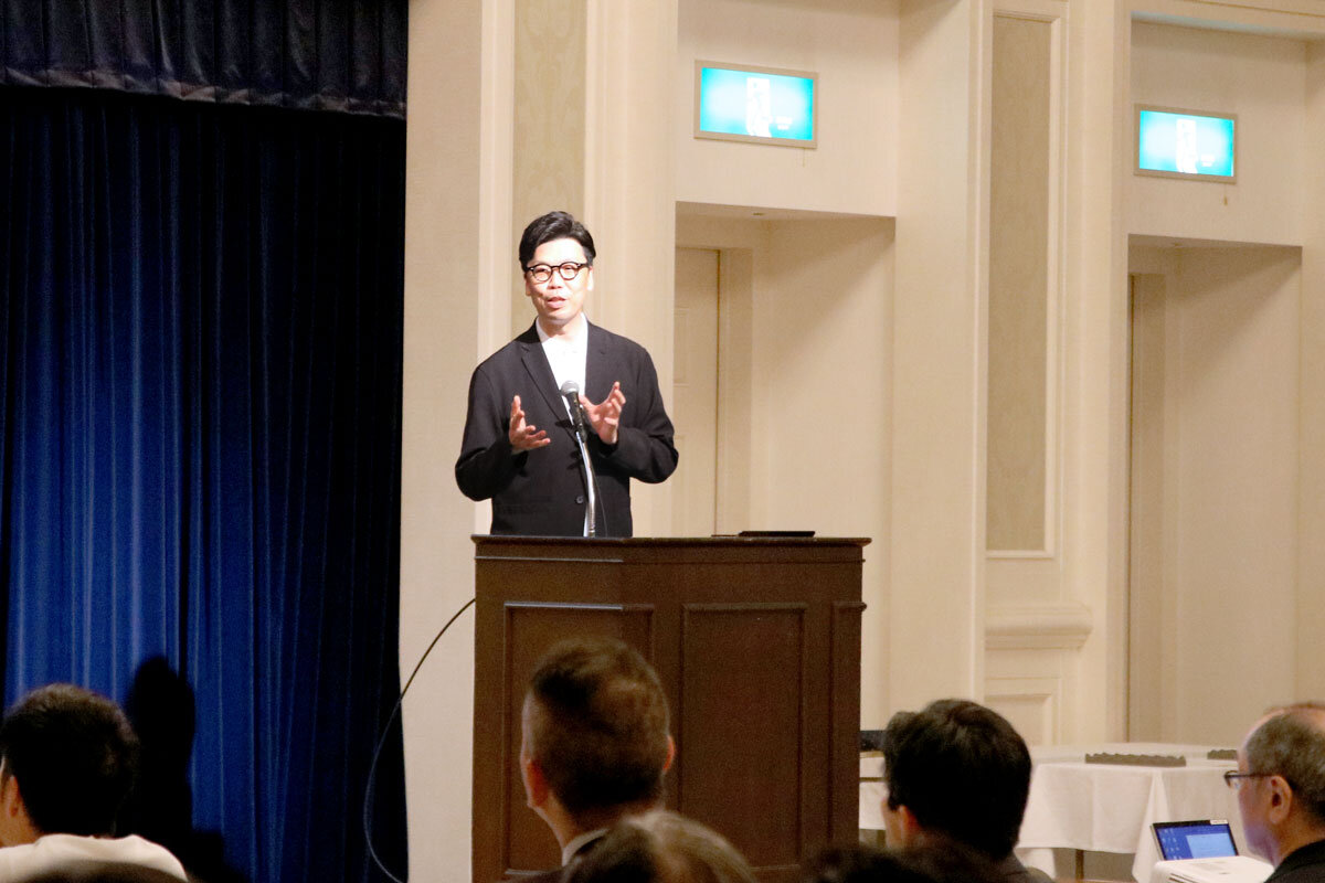 演壇に立ち、参加者に向けてしゃべる石川の姿