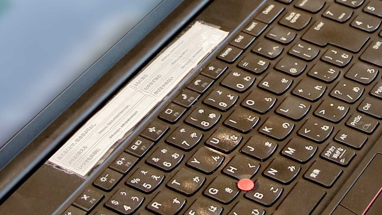 パソコンのキーボードの上、空いたスペースに細長い紙が貼りつけてある。紙には「伝えることで、社会をよりよく。」の企業メッセージと、5つの行動指針が書かれている