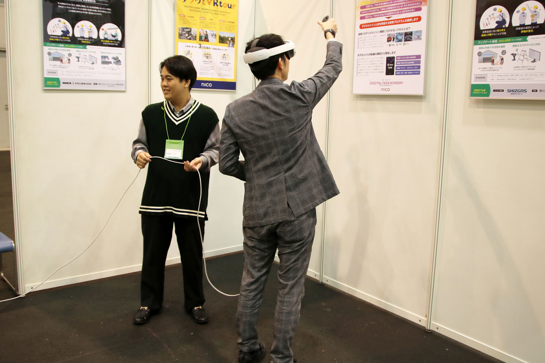 体験中の男性の後ろ姿。頭にヘッドマウントディスプレイを装着し、手にしたコントローラーを持ち上げてVR空間上の何かを操作しているが、現実には何もない空中を動いているだけに見えているいる