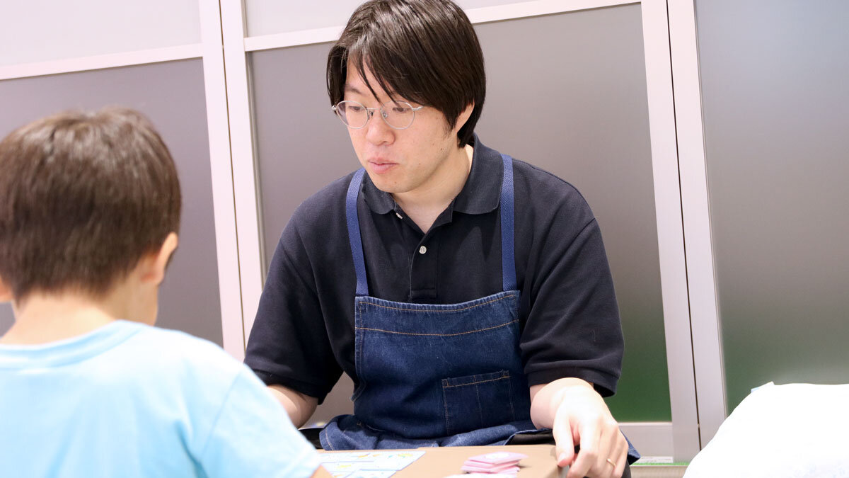 子どもと一緒にボードゲームをする加藤さんの様子